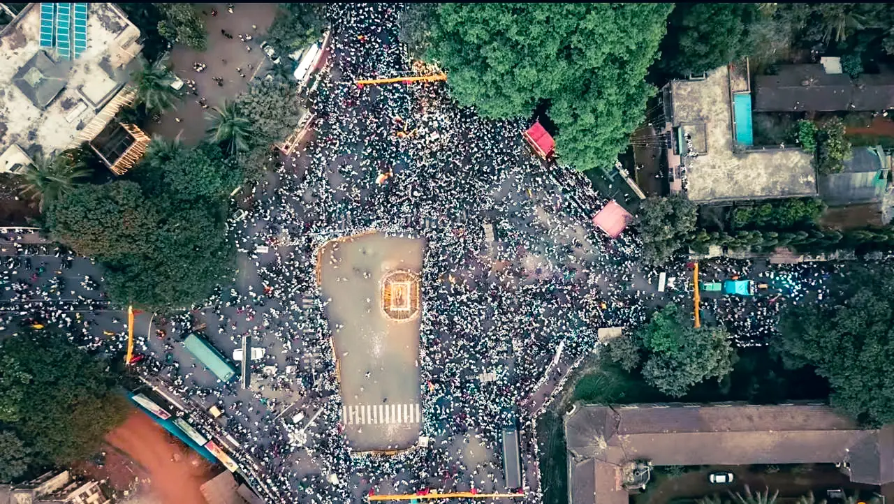 Crowds filling the streets around a decorated chariot, seen from directly above, during Kannada Rajyotsava